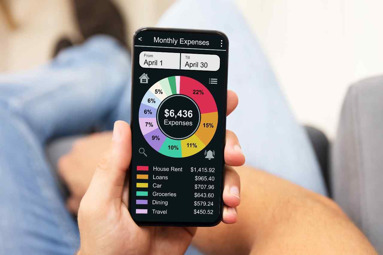 Close up on individual holding phone and looking at budgeting app