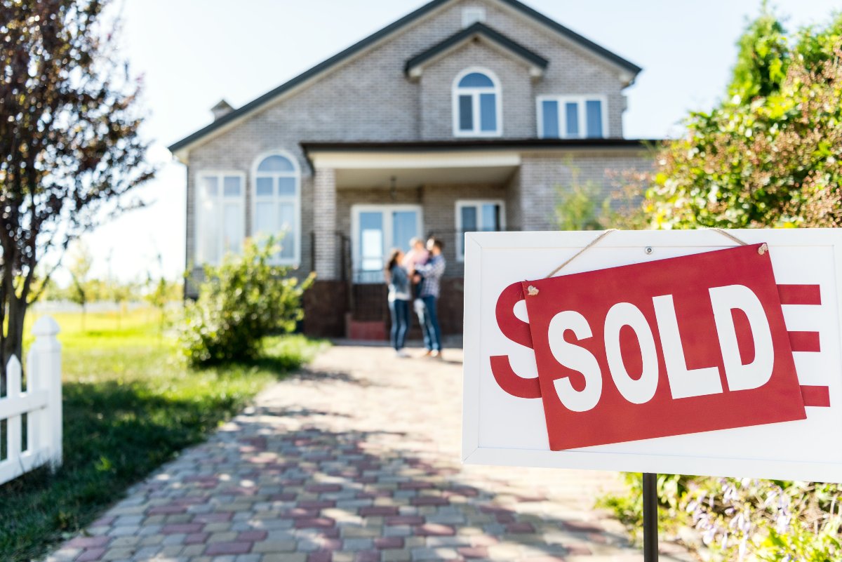 Close up on sold sign in front of house 