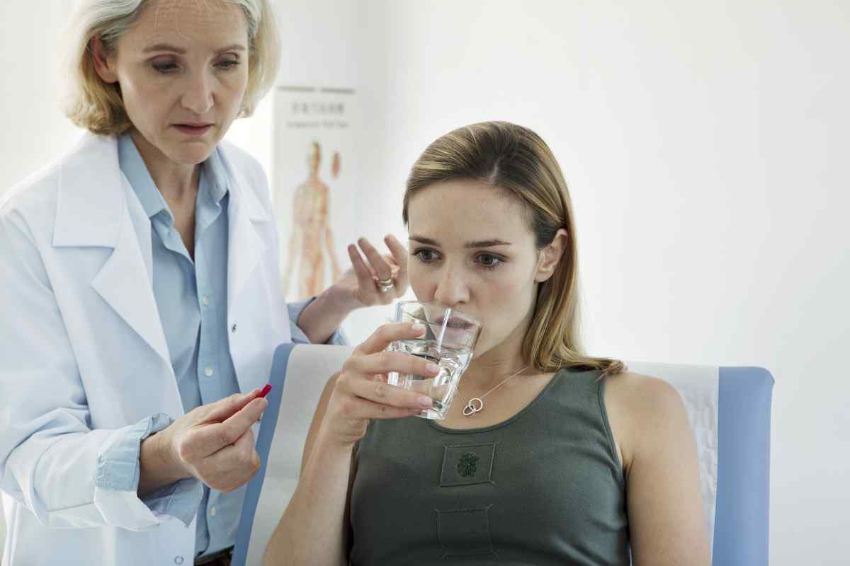 Woman at a clinical trial about to take a red pill and drink some water.