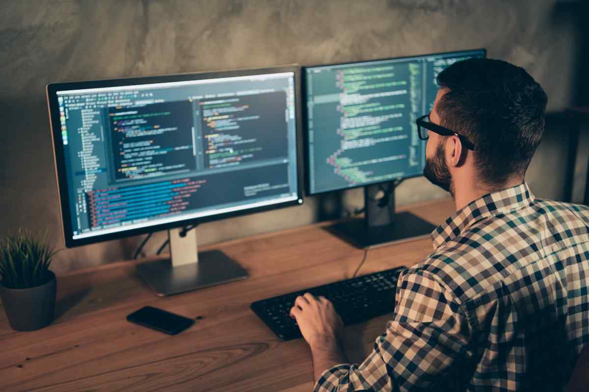 Coder working on computer with two monitors.