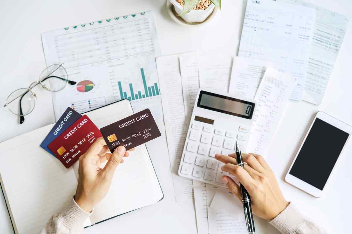 Overhead view of individual holding credit card and using calculator