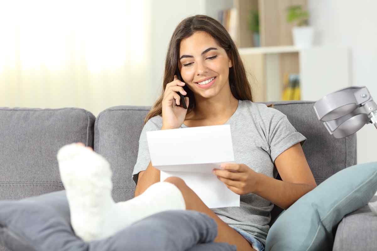 Woman with a hurt foot sitting on a coach talking on the phone.