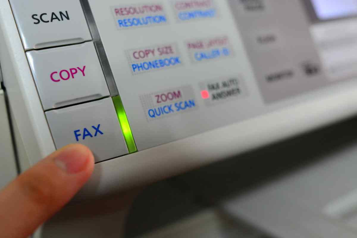 Person pressing a fax machine button.