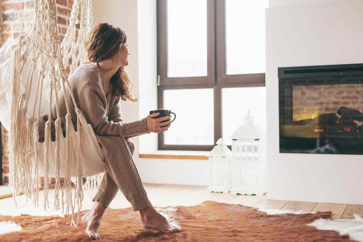 Young adult sitting near fireplace.