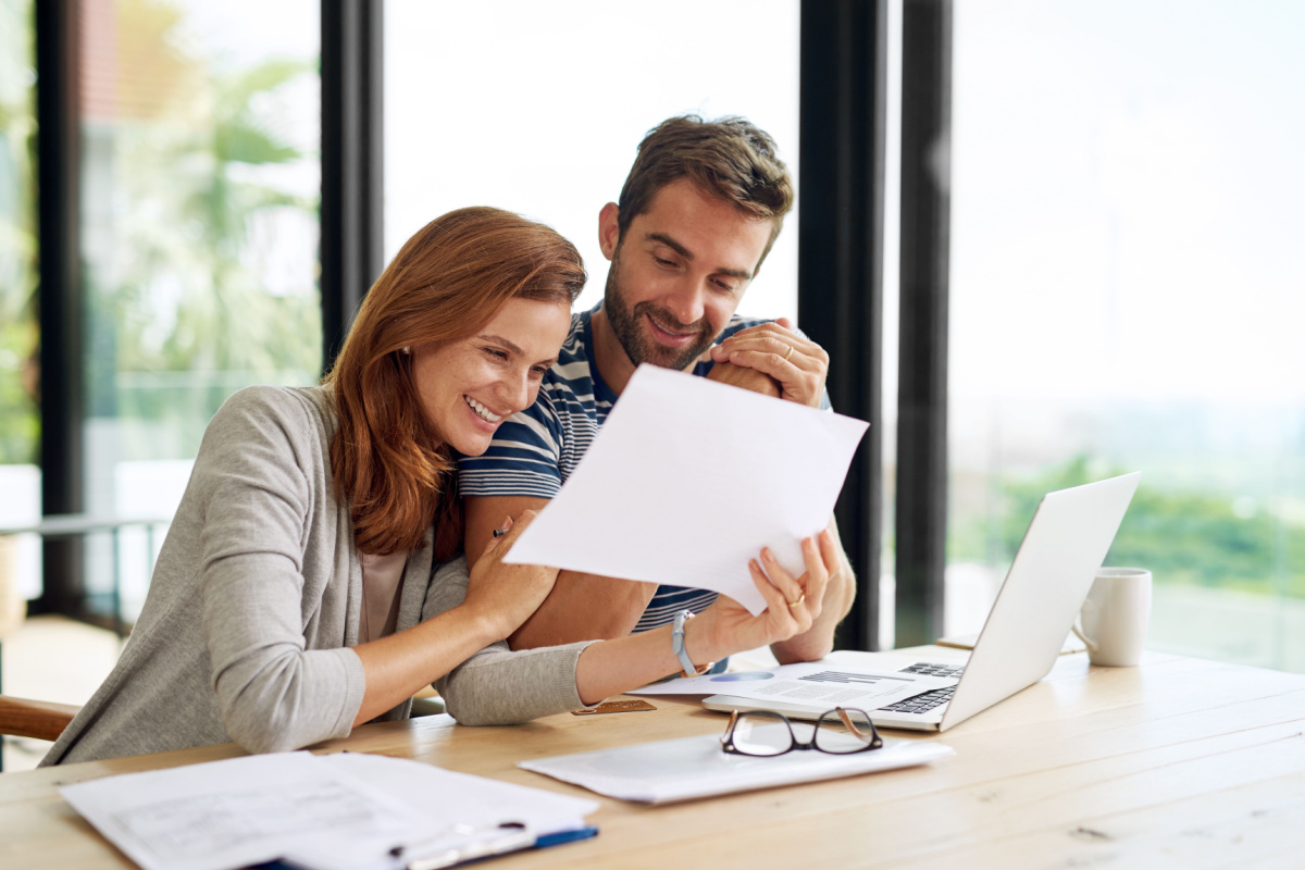 Married couple smiling and looking over financial statements 