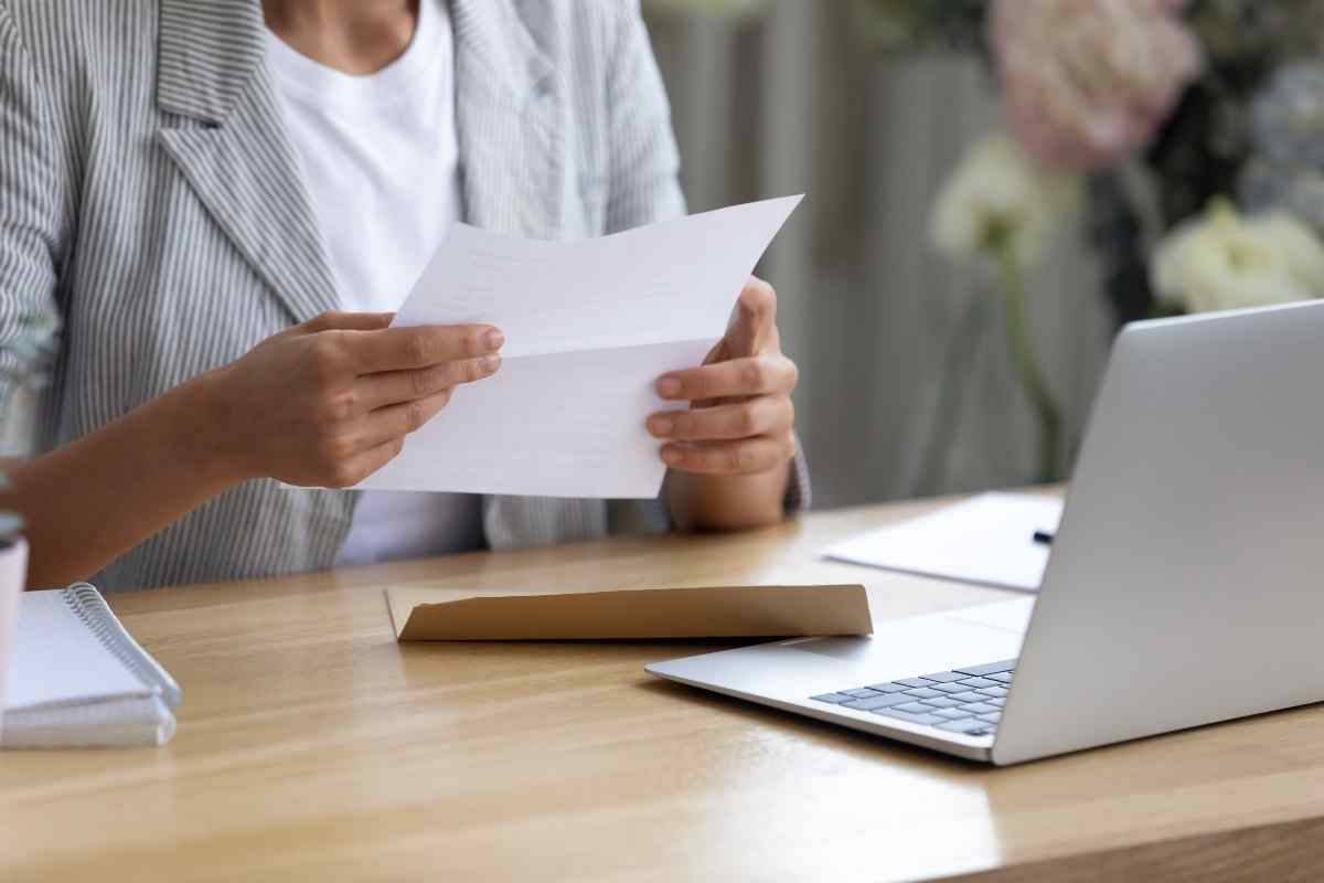 Individual sitting at desk and opening a letter.