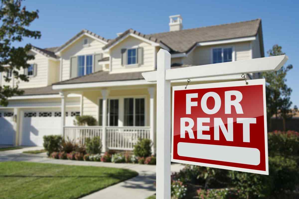 House with a for rent sign on the front lawn