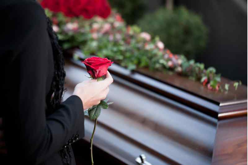 Woman next to the coffin.