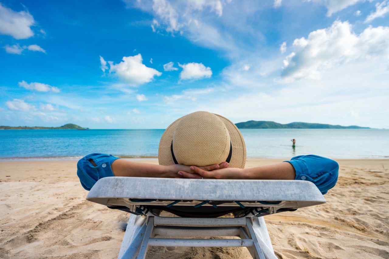 Individual on vacation sitting in a lounge chair on the beach