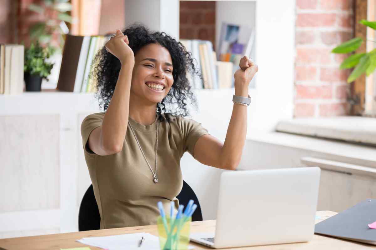 Woman celebrates at desk at work.