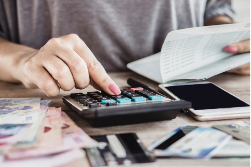 Woman enters numbers from a financial document into a calculator.