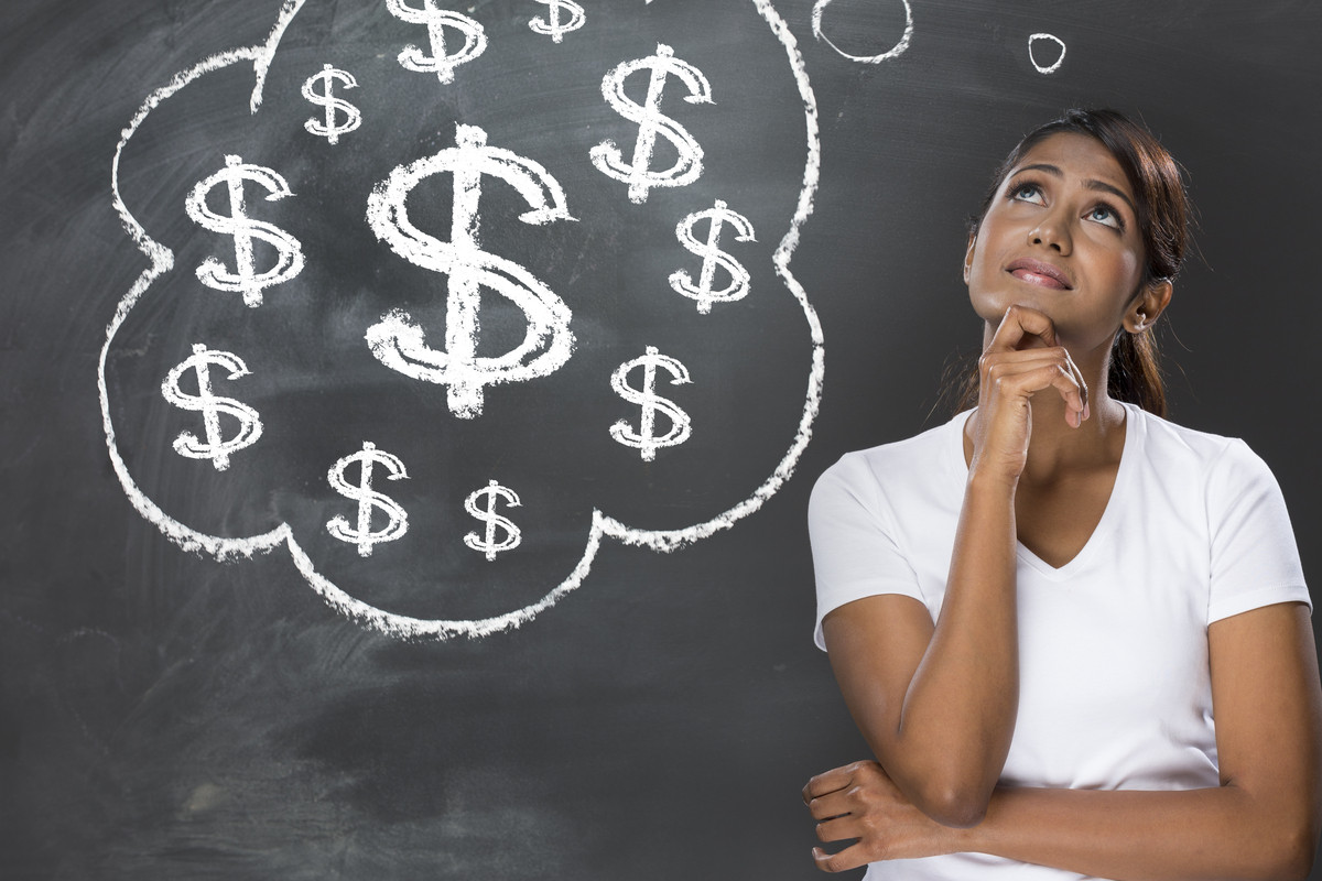 A woman pondering a question in front of a blackboard with question marks drawn on it.