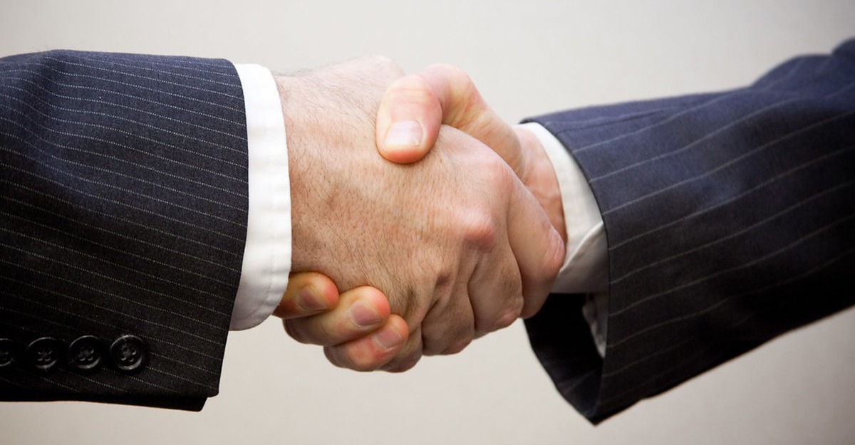 Two suit-wearing men shaking hands.